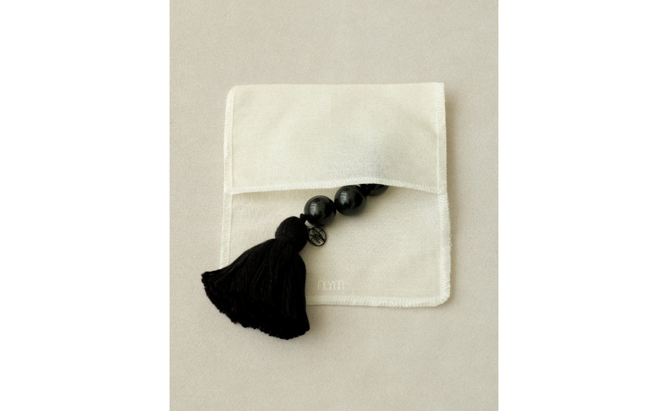 A MYJN black tassel talisman nearly set inside the MYJN linen pouch
