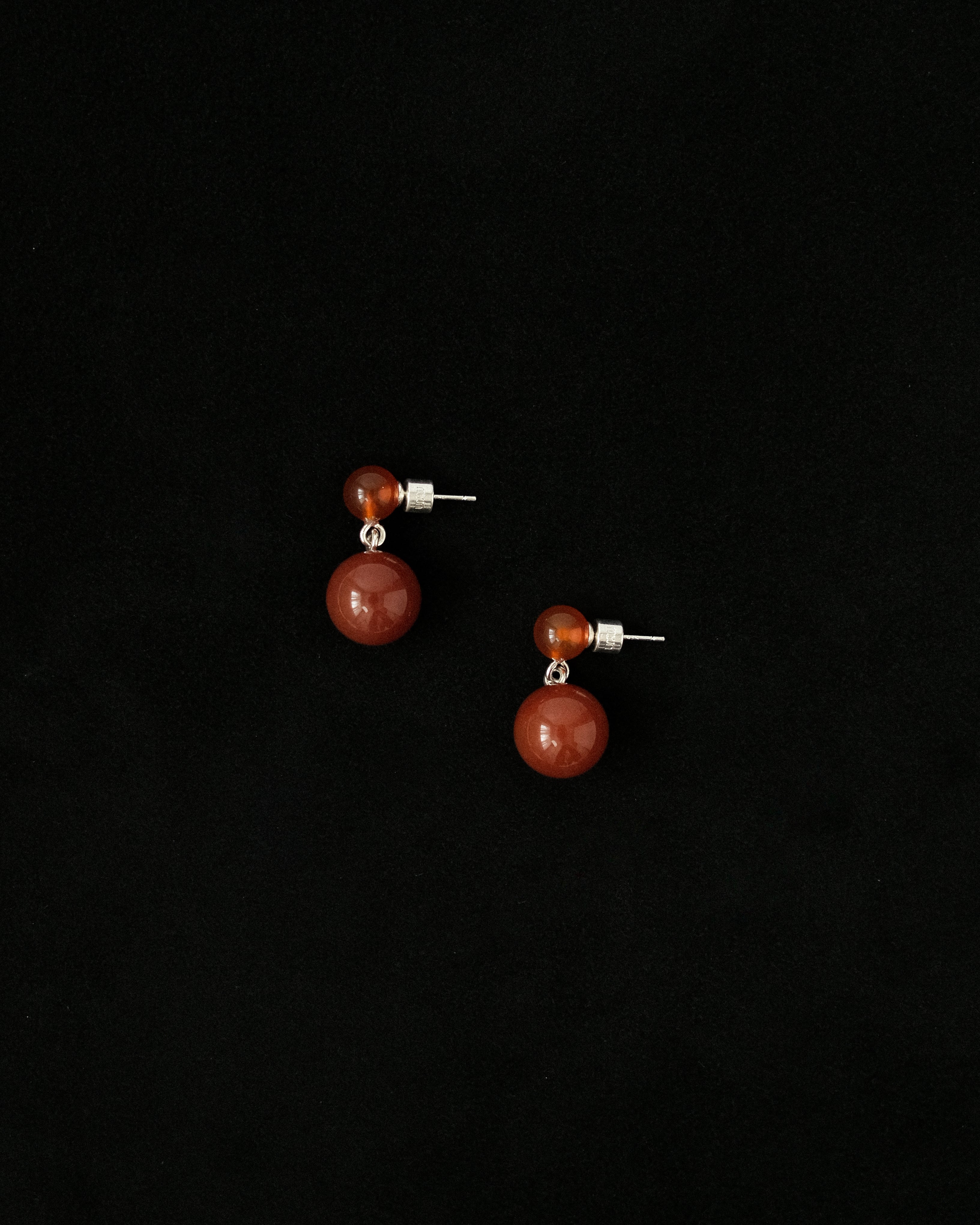 Pair of earrings with red spherical stones on a black background