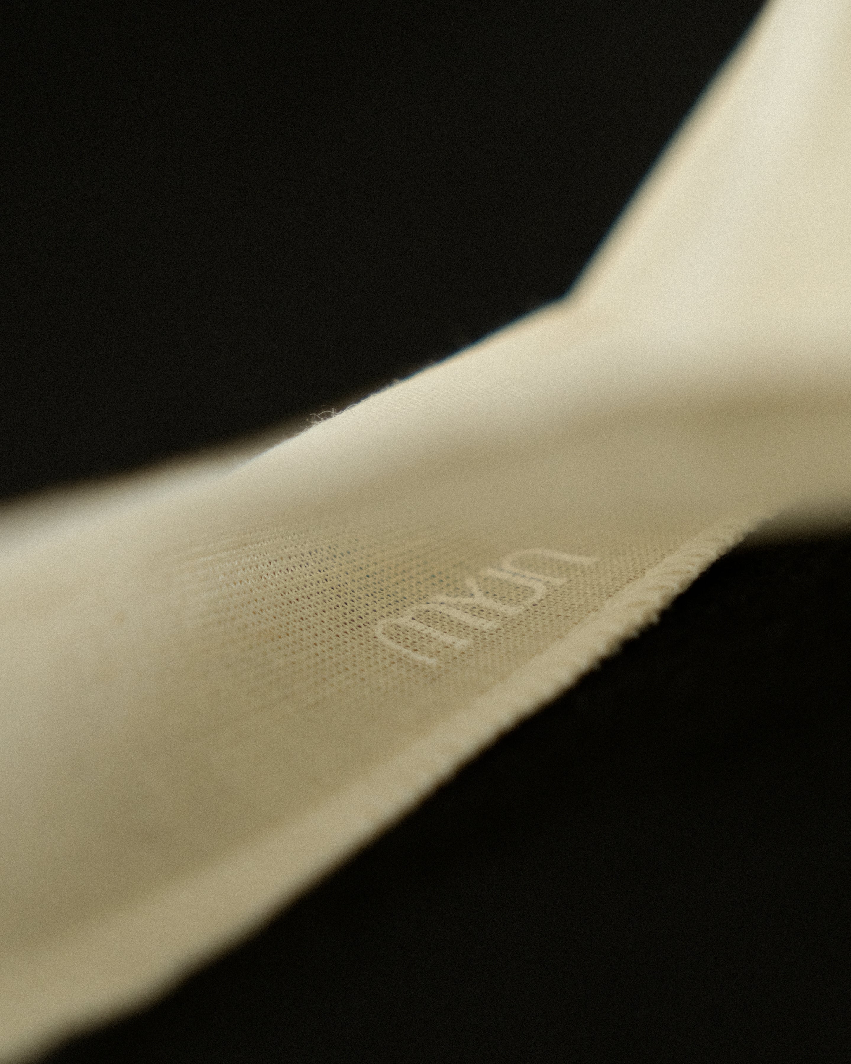 Close-up of a beige fabric with a MYJN logo on a black background