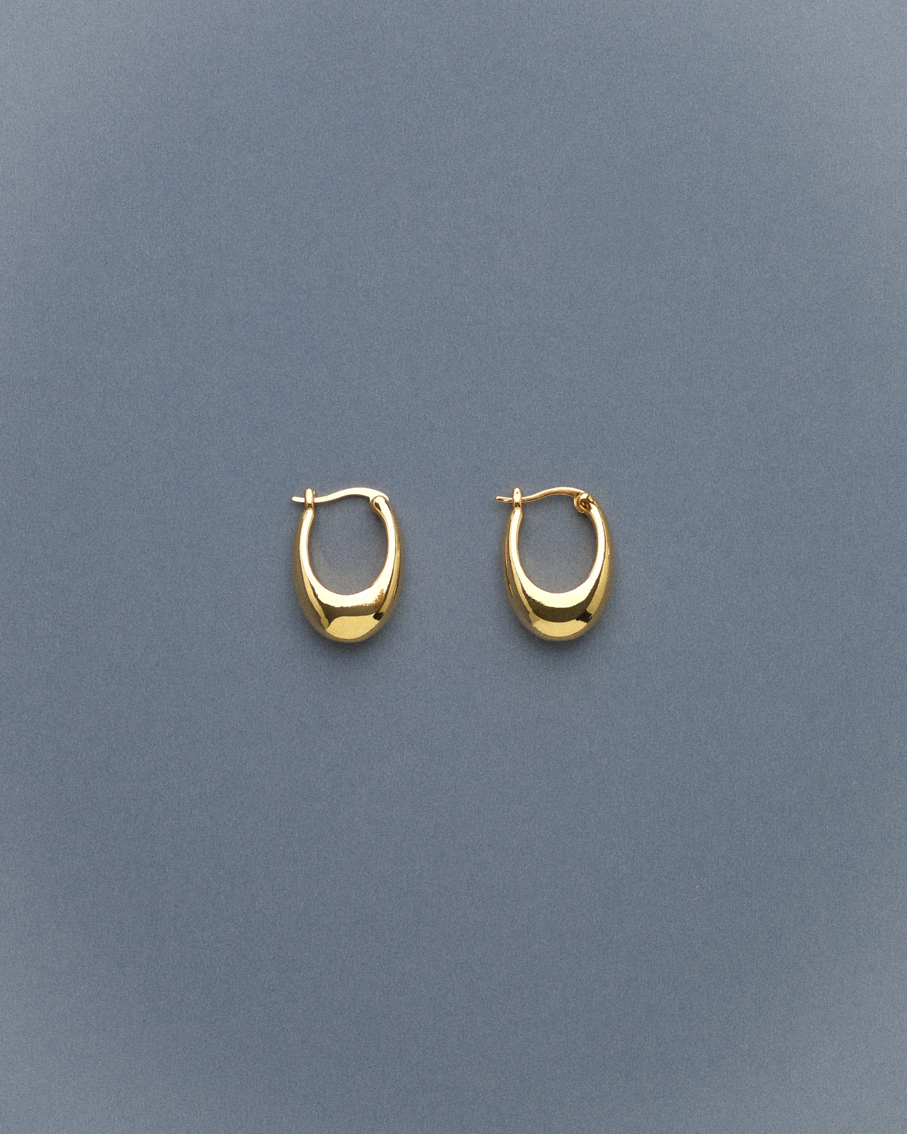 Pair of gold hoop earrings on a grey blue background