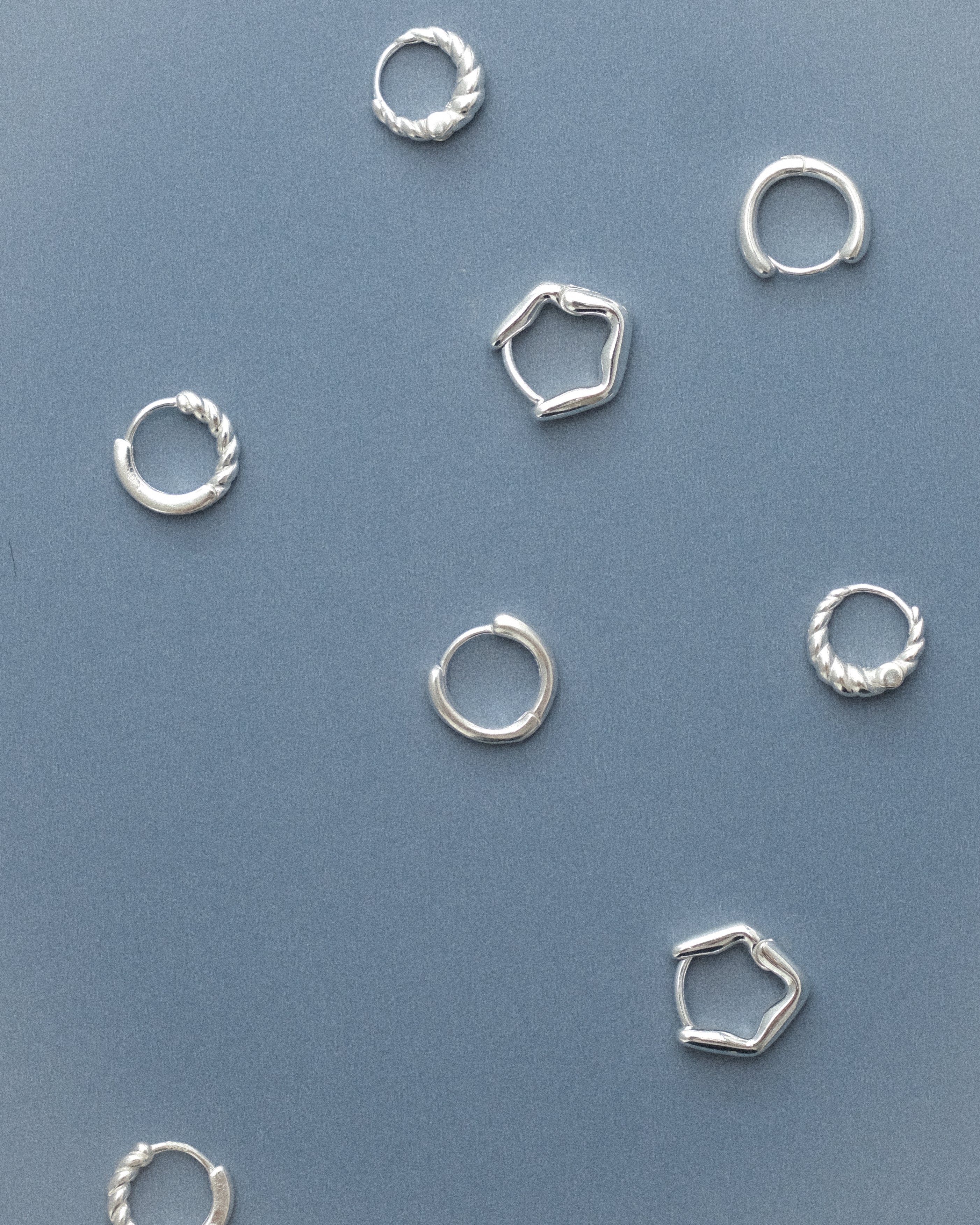 Featuring all classic everyday hoop earrings against a grey blue background.