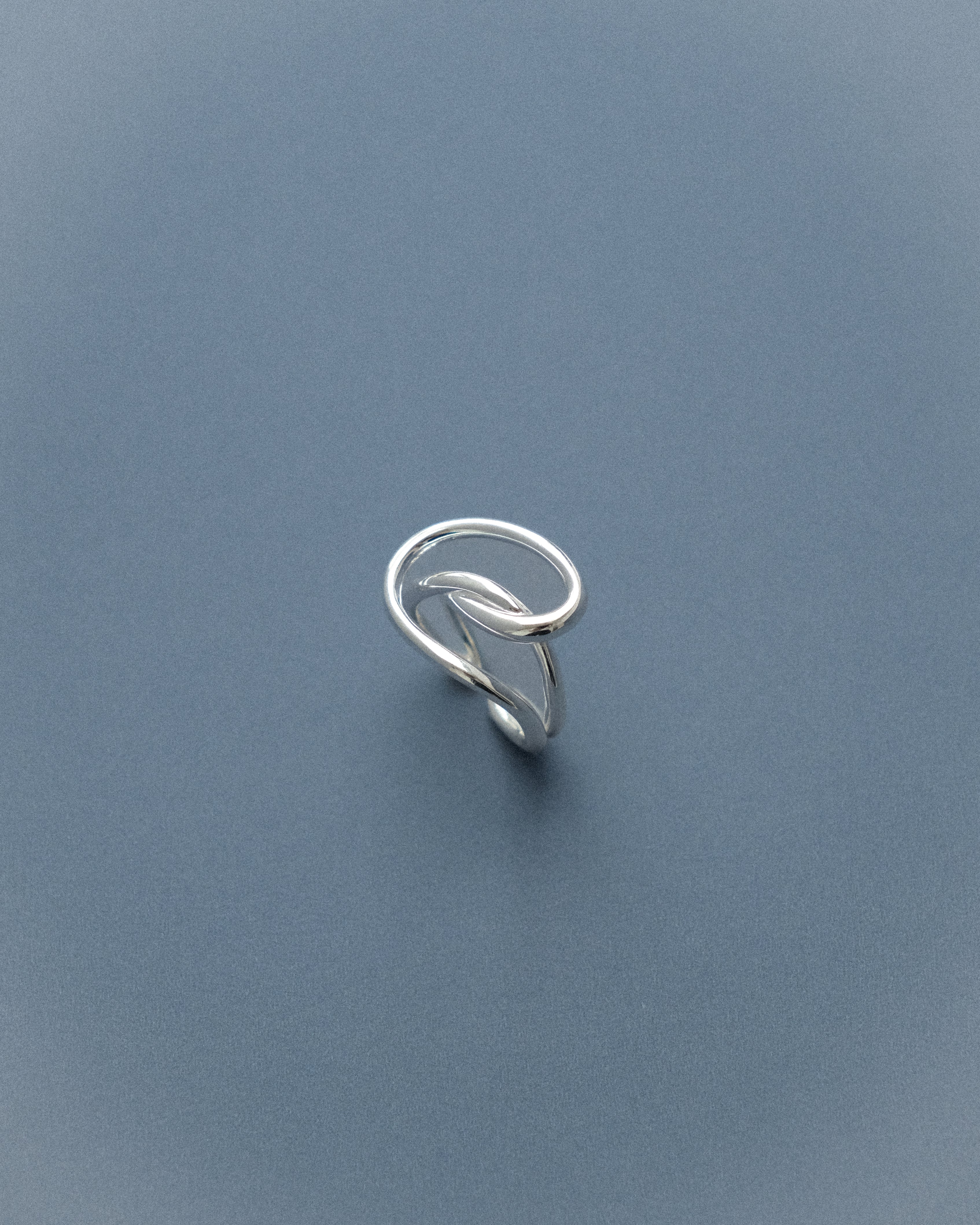 A line sculpture ring set against a serene blue background.