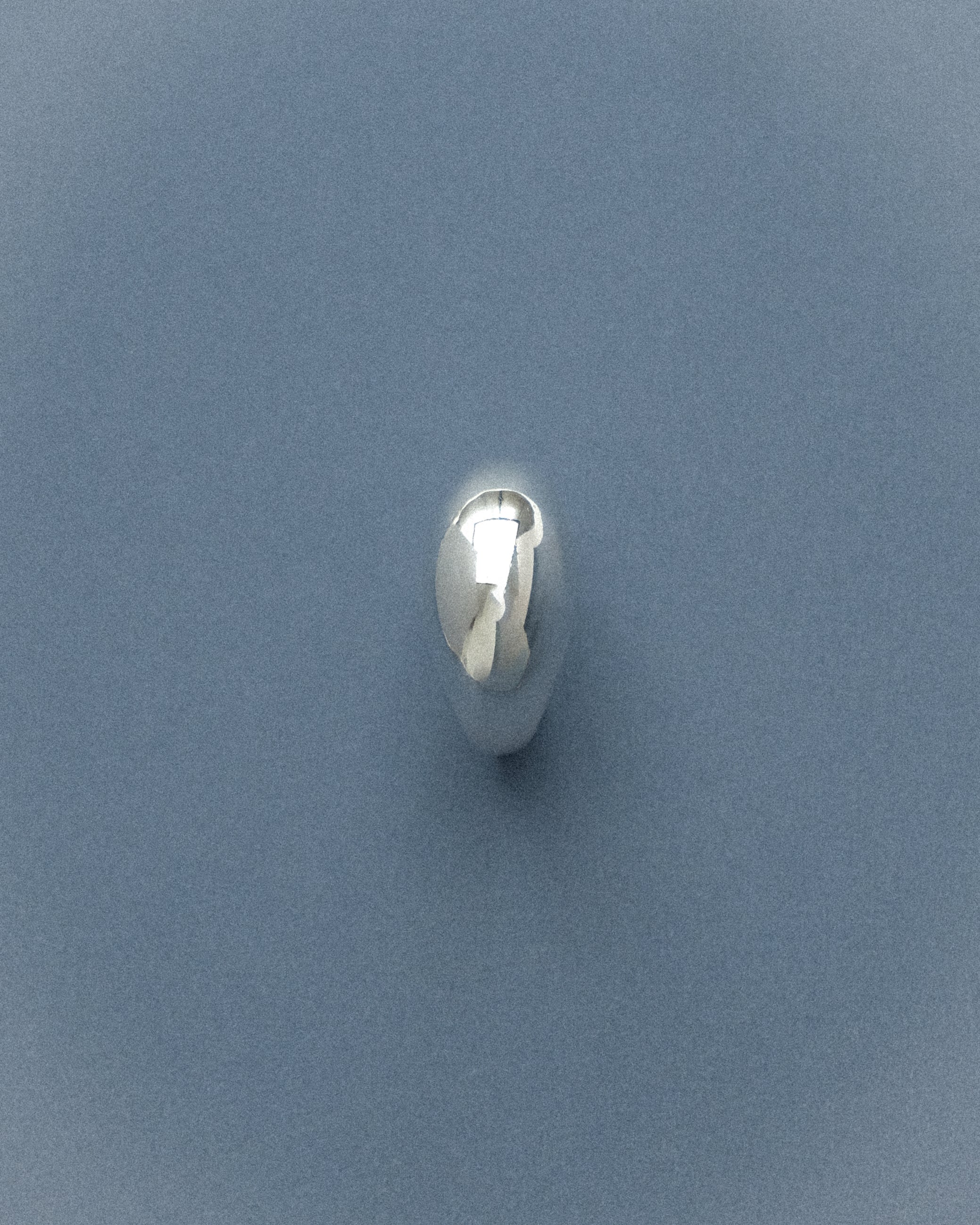 An egg dome silver ring captured in a flat lay from the front-side angle, revealing its rounded, sculptural egg form and subtle presence.