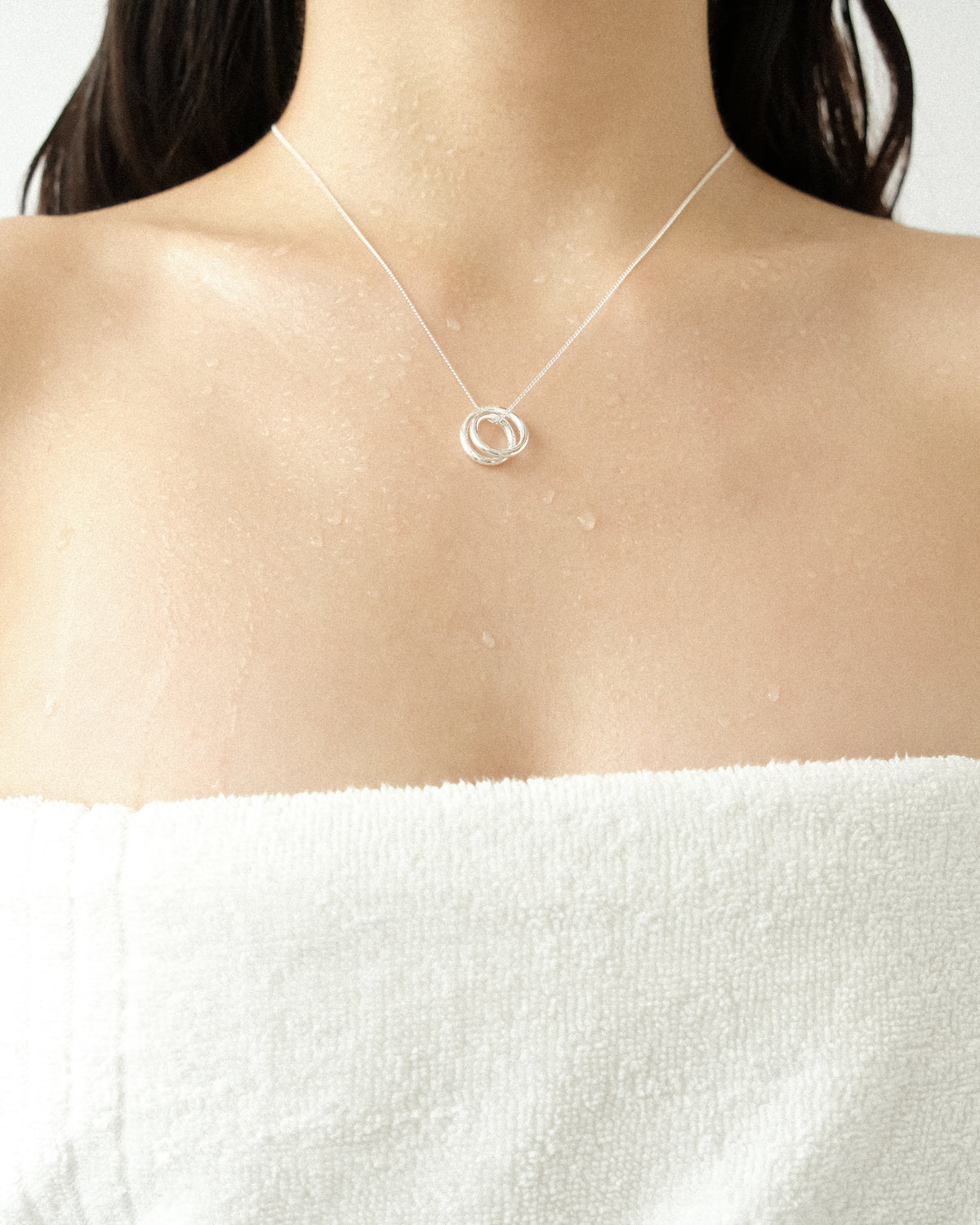Line sculpture pendant necklace worn by a person on a plain background.