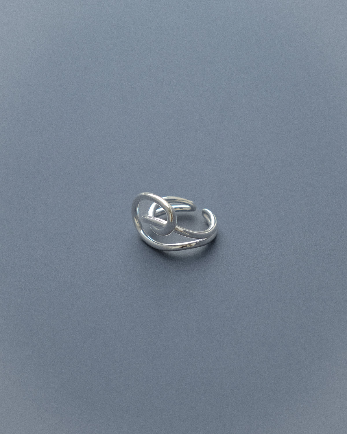 A line sculpture ring set against a serene blue background.