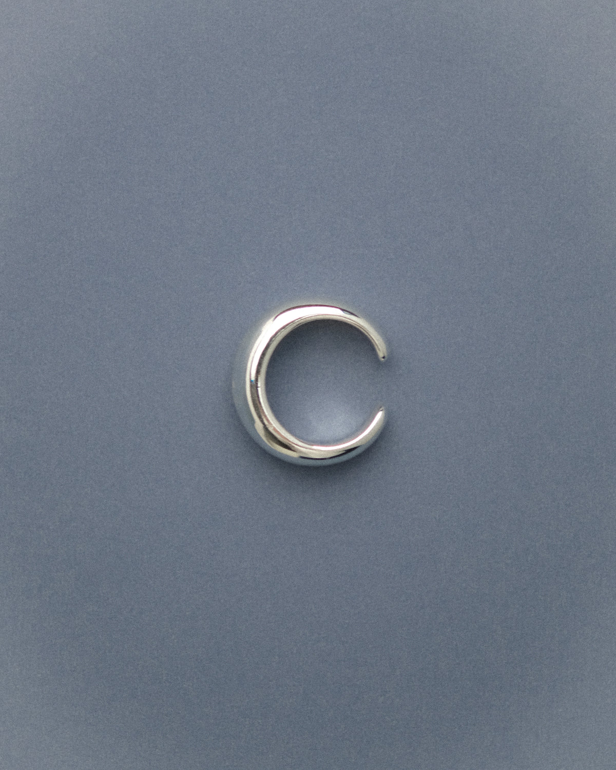 Silver-plated brass open pinky dome ring capture from top against a blue background.