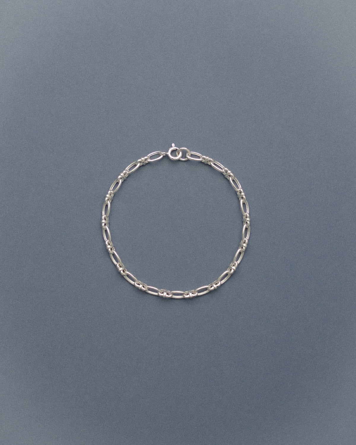 Silver chain bracelet on a gray blue background