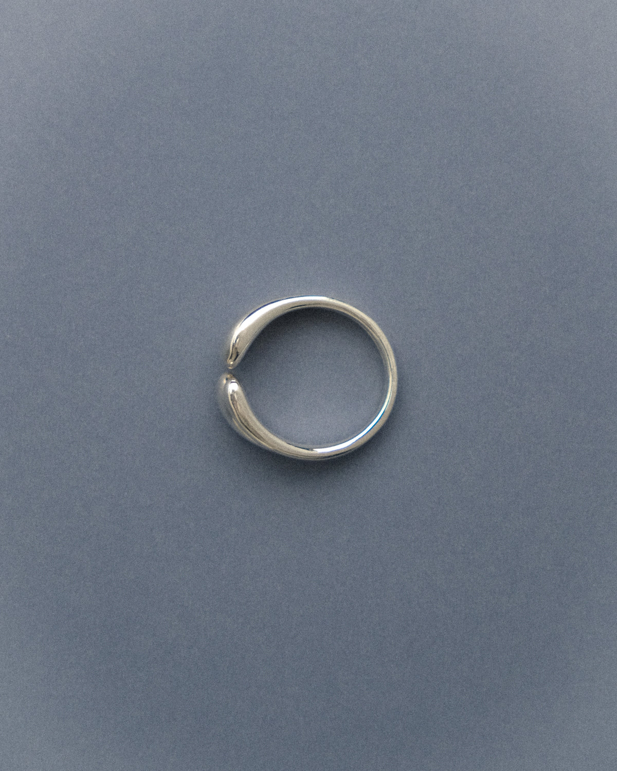 Silver double droplet ring on a gray blue background