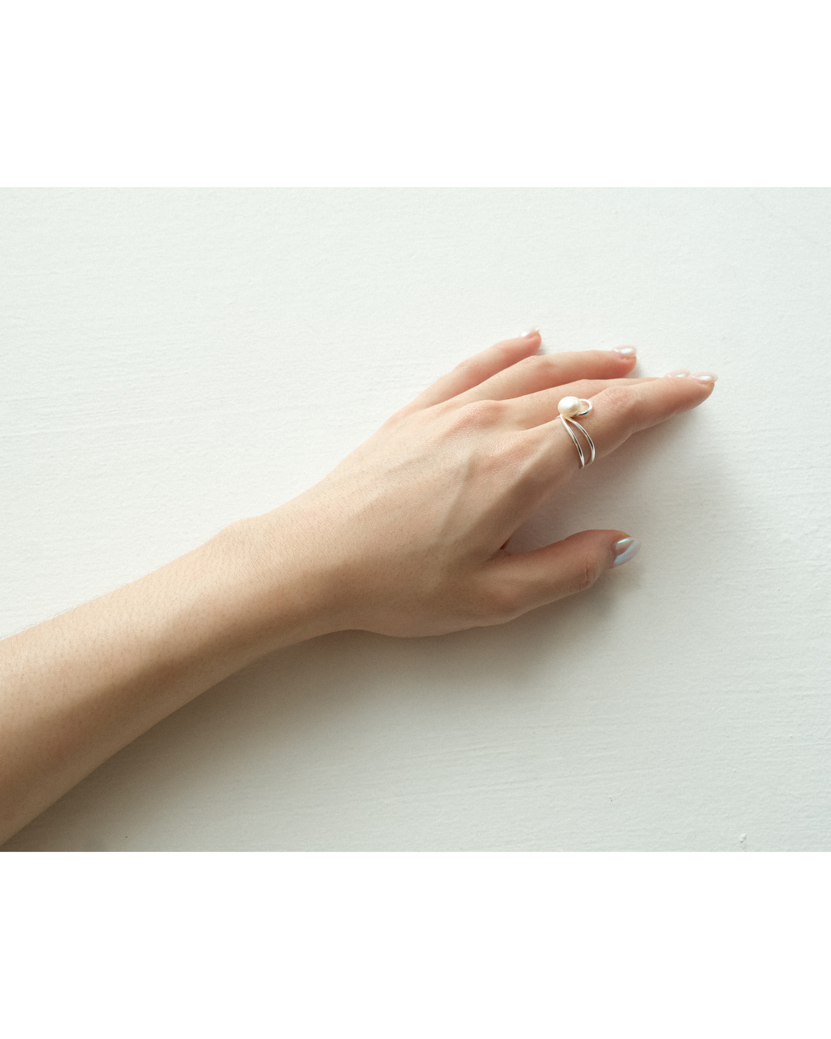 Hand wearing a diadem line fresh water pearl ring on a white background