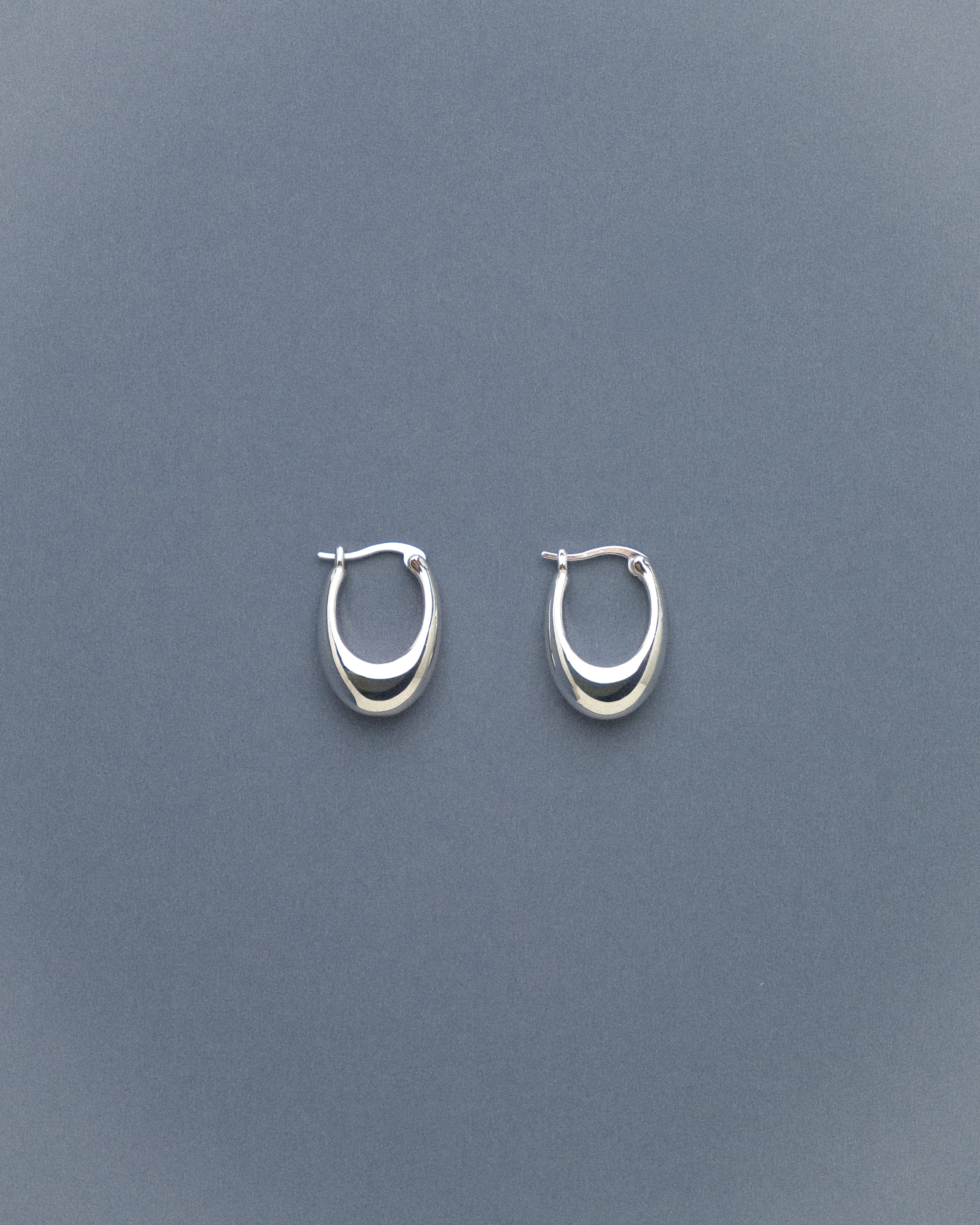 Pair of silver hoop earrings on a grey blue background