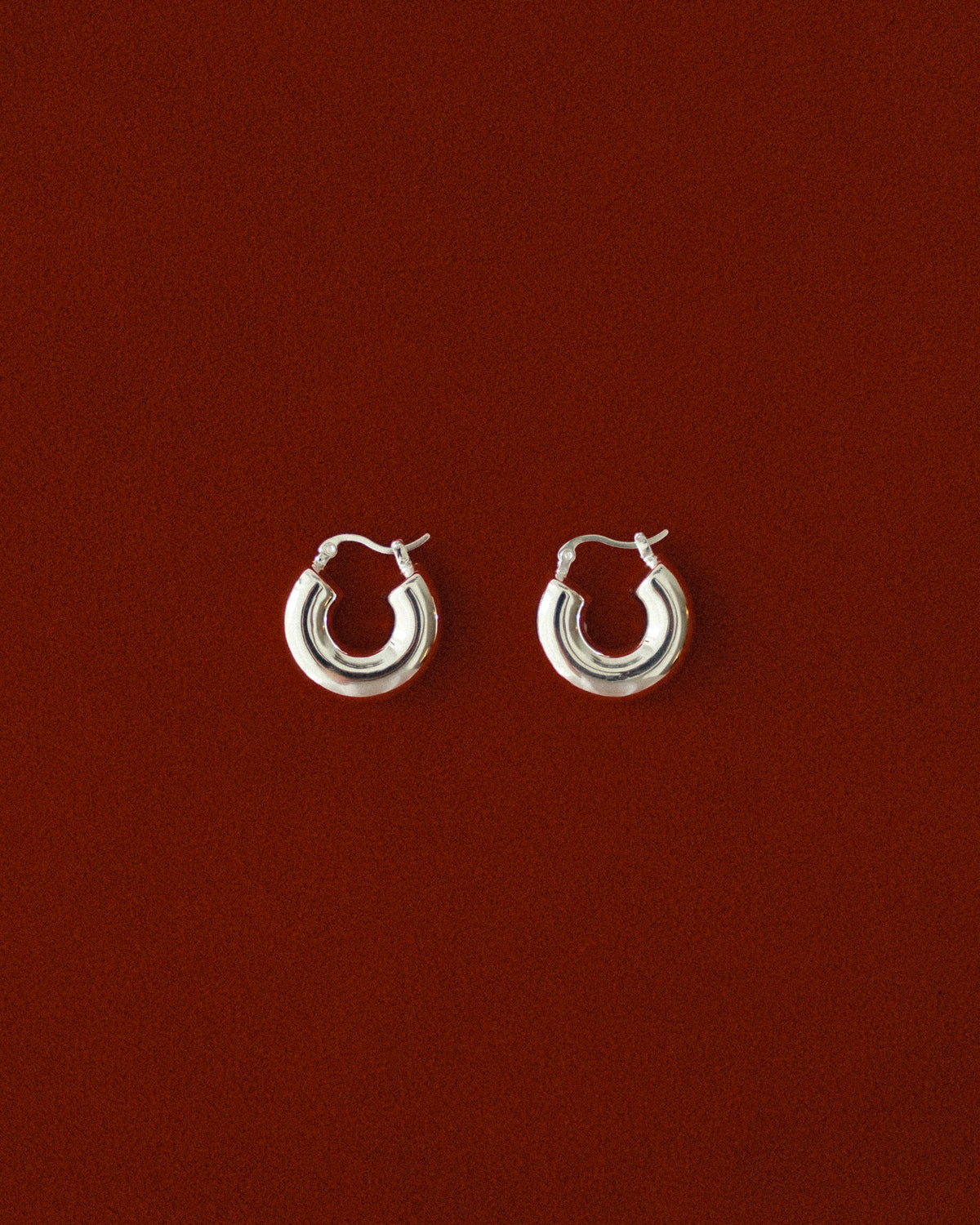 Pair of silver hoop earrings on a red background