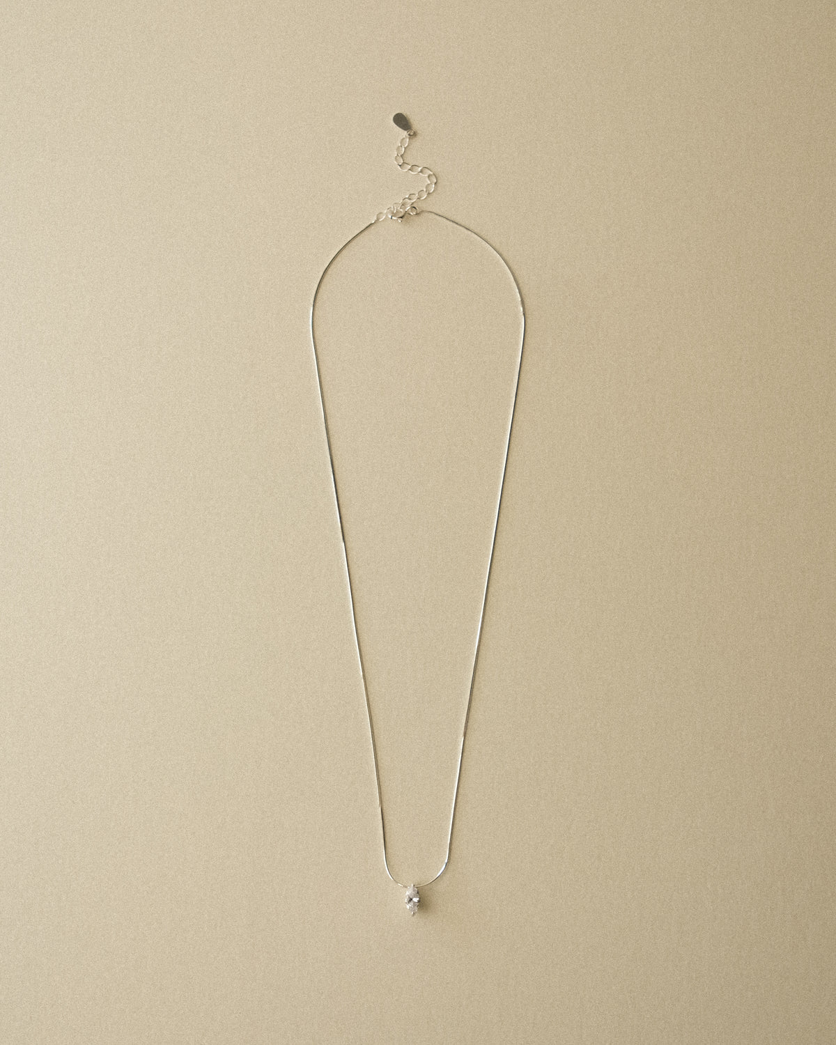 A marquise diamond pendant necklace captured against a warm-toned wabi-sabi backdrop.