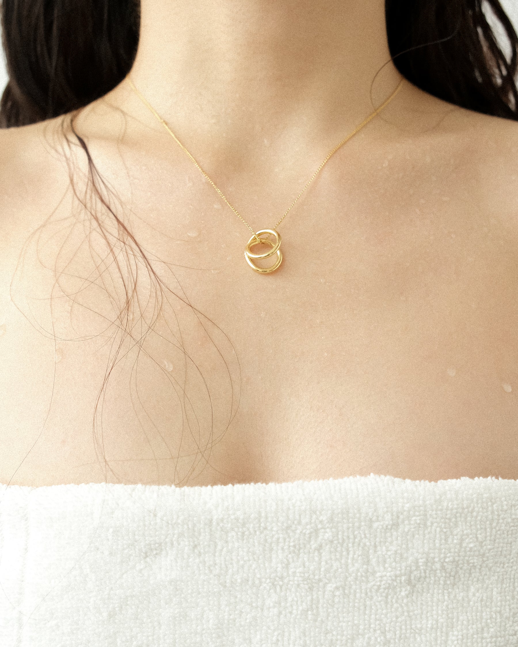 A gold line sculpture pendant necklace graces the wearer against a minimalist backdrop.