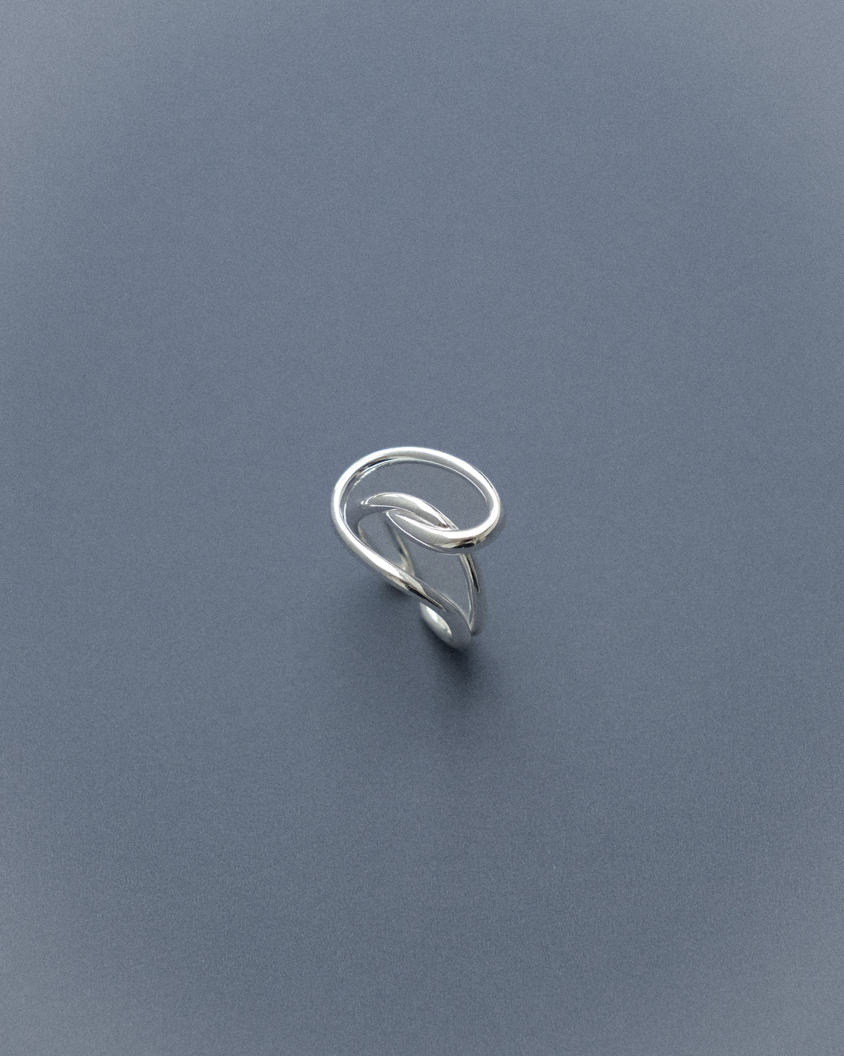 A line sculpture ring set against a serene blue background.