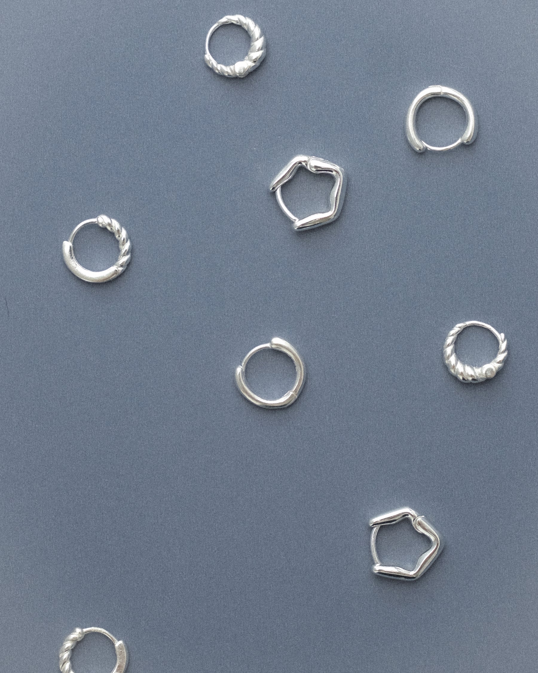 Featuring all classic everyday hoop earrings against a grey blue background.