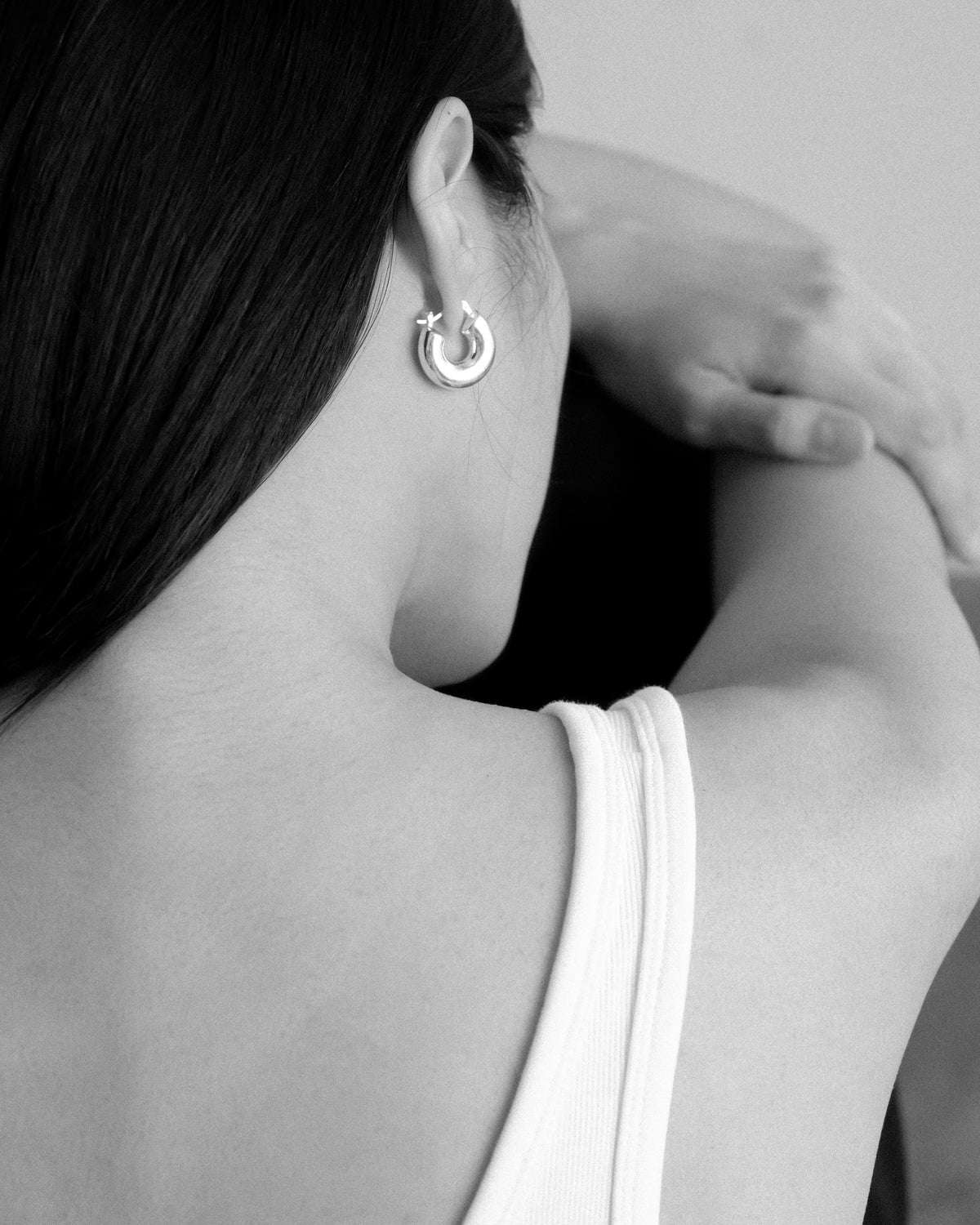Person wearing a silver earring with a small design, black and white photo