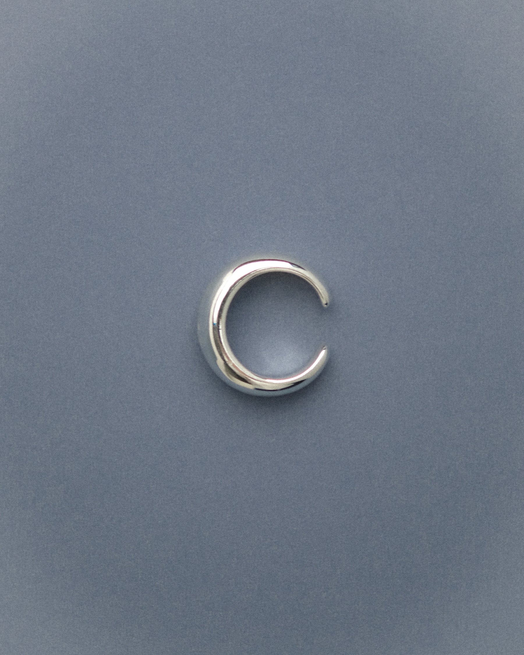 Silver-plated brass open pinky dome ring capture from top against a blue background.