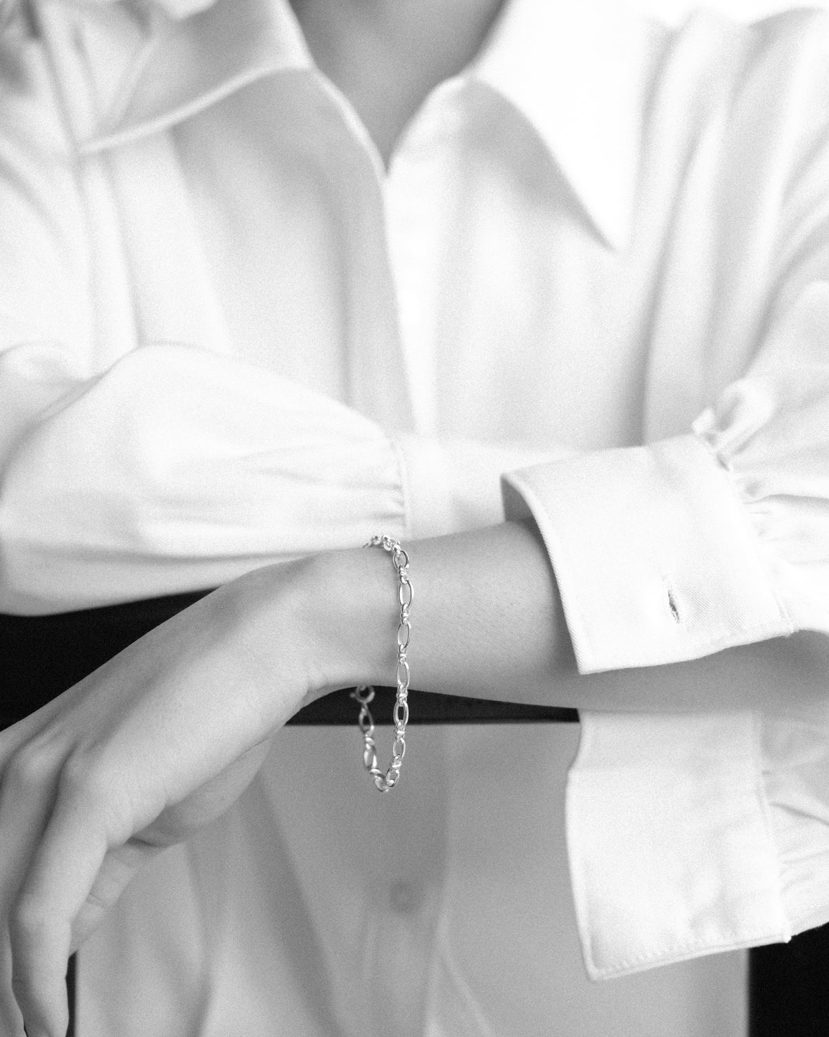 Person wearing a silver bracelet with a white shirt