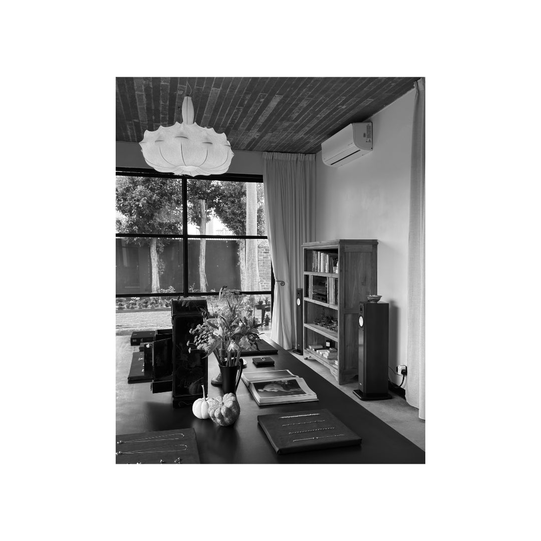 Jewellery display table, bookshelves and garden-facing windows at MYJN Galerie.