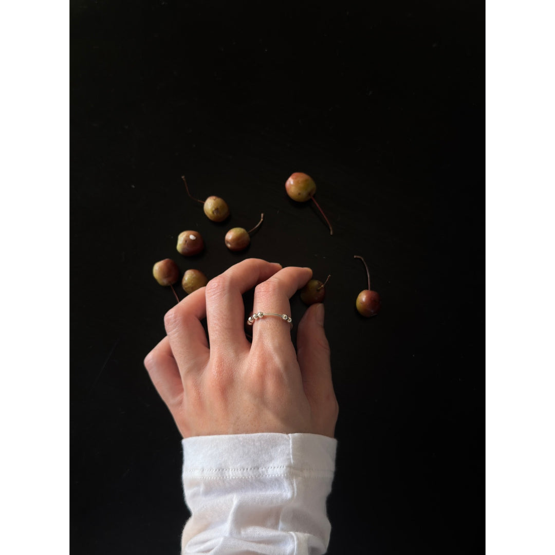 MYJN bead ring on a hand over cherries