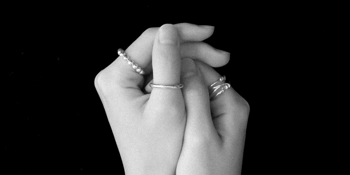 Two clasped hands wearing MYJN sterling silver rings