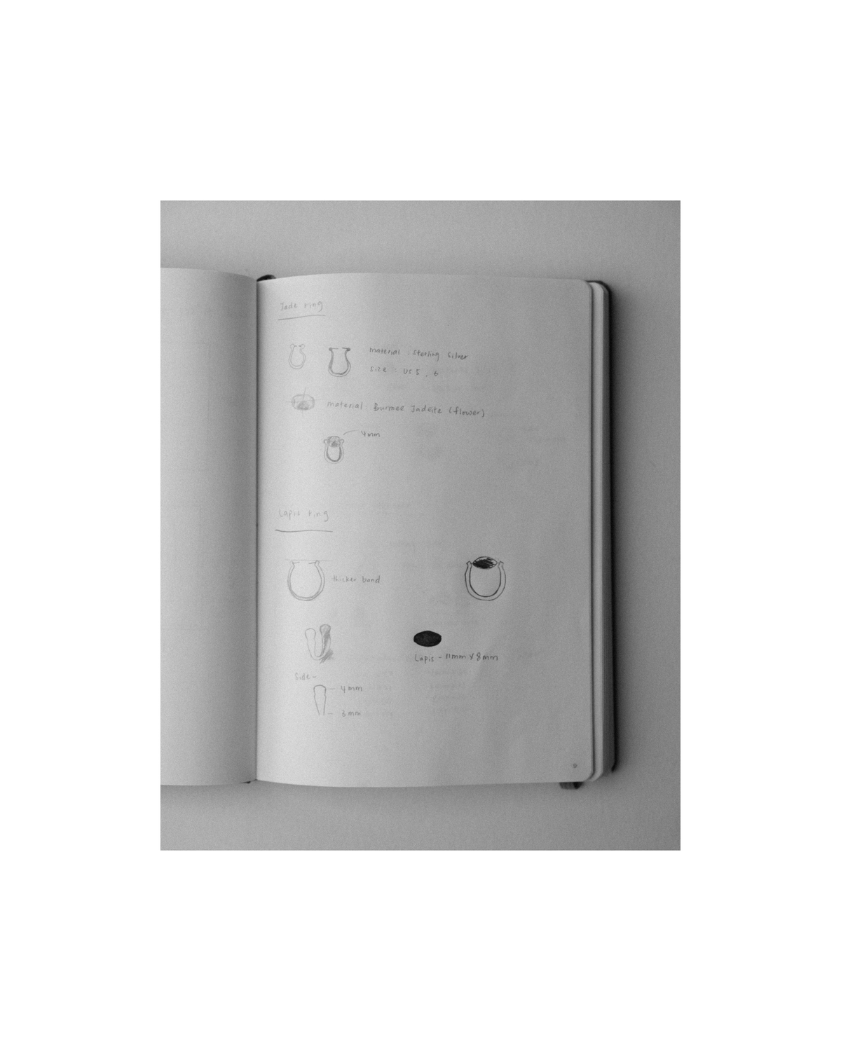 An open sketchbook on a light gray background, showing faint hand-drawn technical diagrams and notes on the pages.
