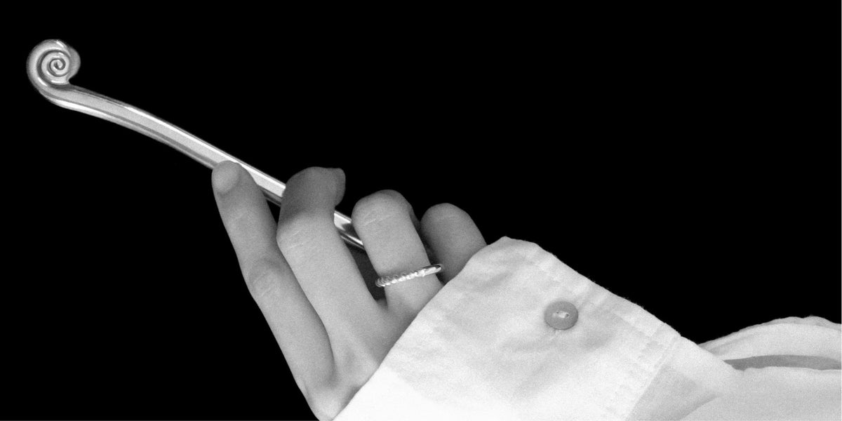 The Brand, MYJN sculptural jewellery. A hand holds a spiral-handled spoon and wears the Anouk ring in sterling silver.
